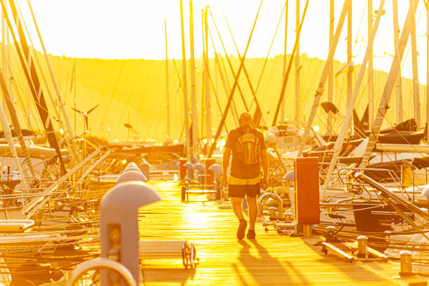 Rear view of unrecognizable man walking on the pier during sunset