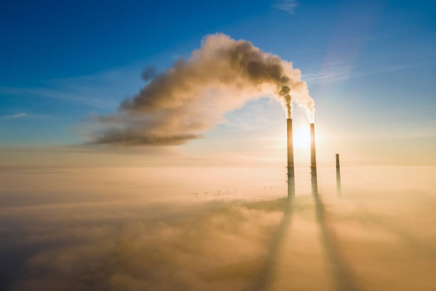 vista aérea de canos altos de usinas de carvão com fumaça preta subindo a atmosfera poluidora ao pôr do sol. - rasto de fumo de avião - fotografias e filmes do acervo