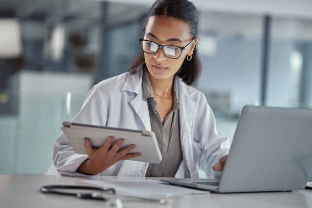 職場でデジタルタブレットを使用して若い女性医師のショット - 電子カルテ ストックフォトと画像