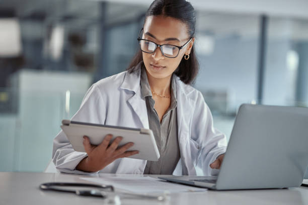 foto de uma jovem médica usando um tablet digital no trabalho - jaleco de laboratório - fotografias e filmes do acervo