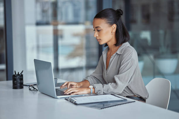 Shot of a young businesswoman using a laptop in an office at work stock photo