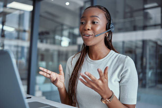 scatto di una giovane agente di call center donna che usa un laptop al lavoro - internet computer hands free device telephone foto e immagini stock