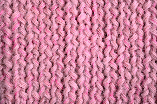 Knitwear in calm pink is on the table - this is the fashionable color trend of 2022. View from above. Flat lay, top view, close-up, macro, can be used for background.