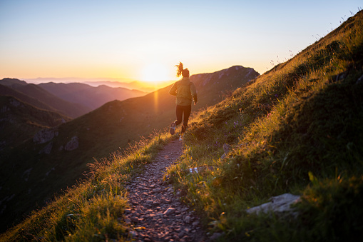 Young woman jogging in the mountains on sunset.