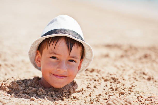 Young boy head on sand wear panama hat. Funny summer vacation.