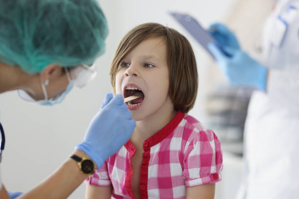The doctor in the clinic looks at the throat of a girl stock photo