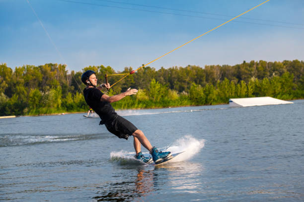 istock Focused man sliding on wakeboard on water surface holding tow rope with one hand 1366021644