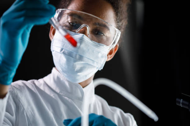 istock Female lab tech analyzing the red liquid in a test tube that she is holding 1366023185