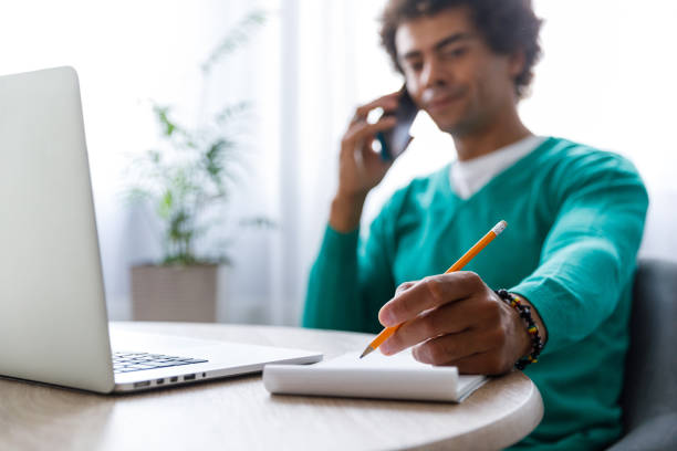 Male entrepreneur on a conference call writing notes