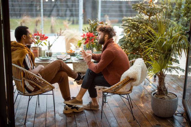 istock Two multiracial male friends having close conversation, sitting by a dinner table at backyard 1366025031
