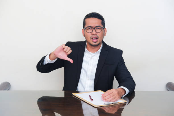 Asian manager wearing black suit give bad evaluation sign during interview process Asian manager wearing black suit give bad evaluation sign during interview process kantor stock pictures, royalty-free photos & images