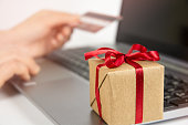 Woman hands holding credit card and using laptop, gift box on keyboard