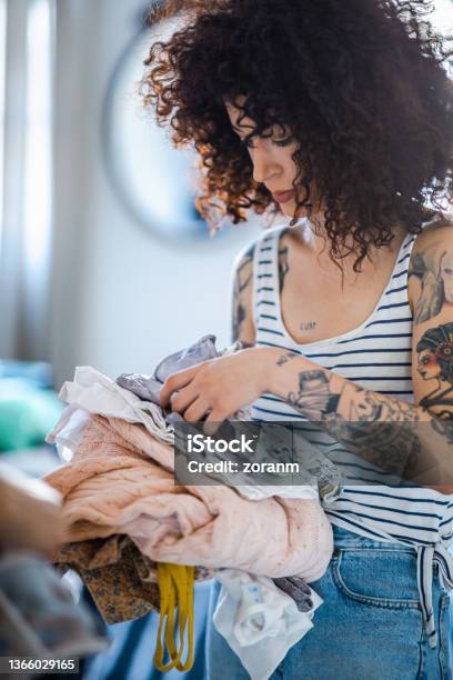 Young Woman Holding Clothes Prepared For Donation At Home Stock Photo - Download Image Now