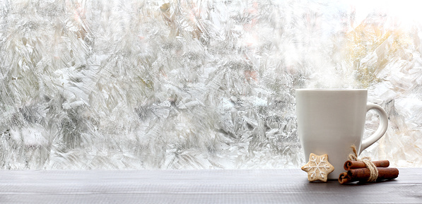 frosty patterns on the window and a mug of cookies and cinnamon. warming coffee overlooking a winter morning