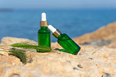 Natural essential oils or serum in dropper bottles standing on the stones at the seaside