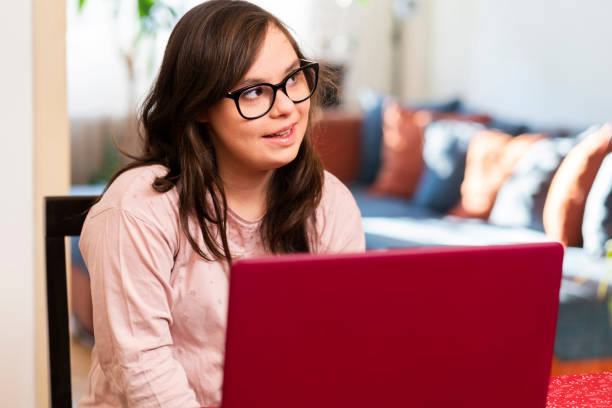 istock Young woman with Down Syndrome using laptop at home 1366039545