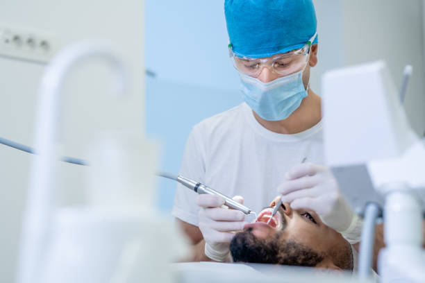 istock Male dentist treating a male patient teeth 1366039593