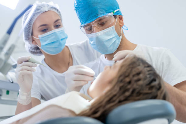 istock Male dentist examining a female patient's teeth 1366039606