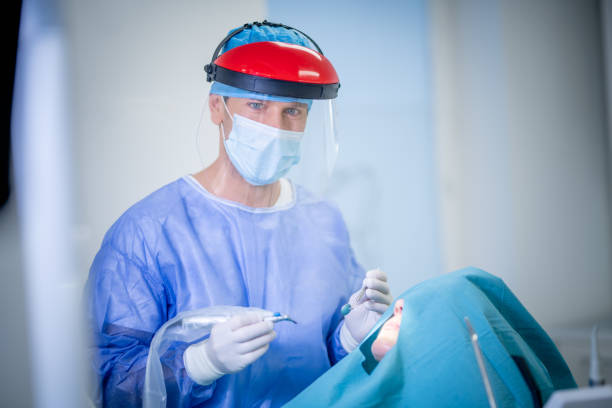 istock Male dentist treating patient with a laser device 1366040350
