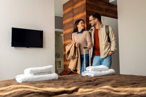 Smiling couple with suitcase arriving in hotel room. stock photo