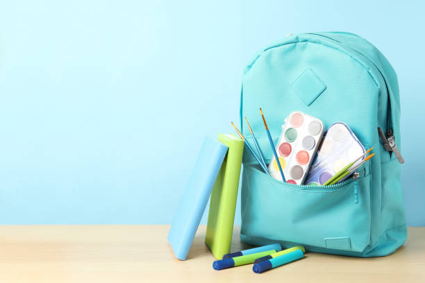 istock Stylish backpack and different school stationery on wooden table against light blue background, space for text. Back to school 1366043929