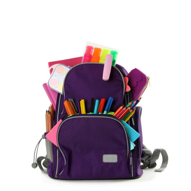 白い背景に異なる学校の文房具を持つ紫色のバックパック - バックパック ストックフォトと画像