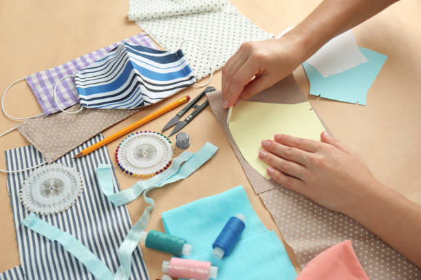 istock Woman making sewing template for cloth mask at table, closeup. Personal protective equipment during COVID-19 pandemic 1366047060