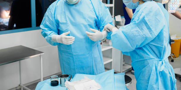 chirurgen tragen sterile handschuhe - operationskittel stock-fotos und bilder