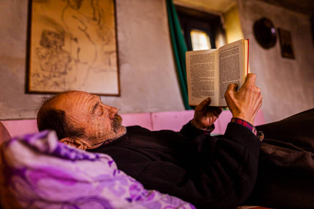 istock Homeless senior men, reading the book while lying on the bed 1366051028