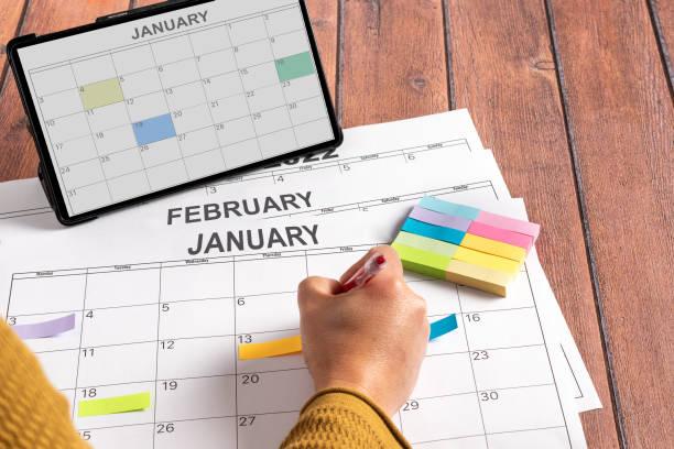 istock Unrecognizable person making notes of the most important activities to be performed during the month, using colored post it notes and using his tablet. 1366051132