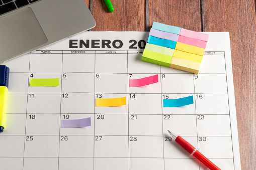 Calendar of the month and several colored Post-it notes to highlight the activities to be done. Copy space. Concept of time organization and achievement of objectives. High quality photo