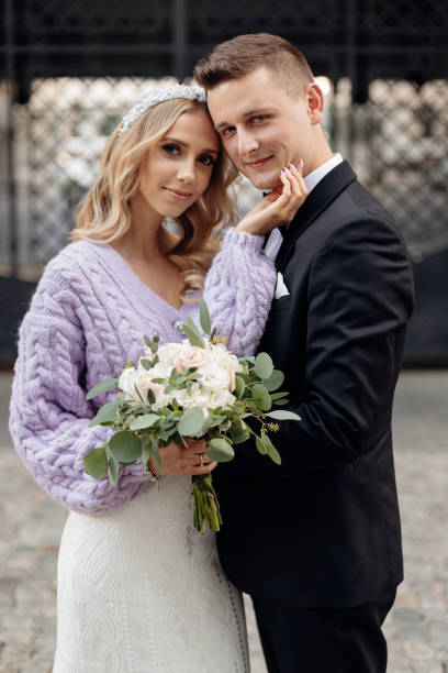 hochzeitsporträt der blonden braut im brautkleid und fliederjacke und bräutigam im schwarzen anzug, der im freien steht - bride caucasian wedding ceremony close up stock-fotos und bilder