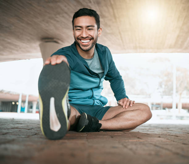 scatto di un giovane che si allunga prima di una corsa - fitness foto e immagini stock