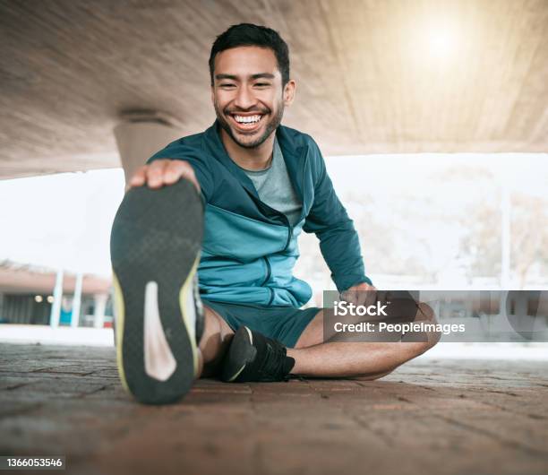 Shot Of A Young Man Stretching Before A Run Stock Photo - Download Image Now - Exercising, Healthy Lifestyle, Running