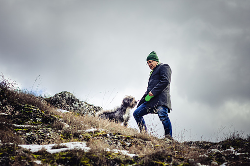 Mature man walking with dog on hill