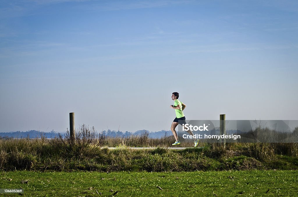 Running Male runner at sprinting speed training for marathon outdoors on country landscape. Activity Stock Photo