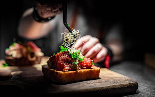 Le chef décore à la main les aliments sur une assiette en bois dans la cuisine du café - Photo