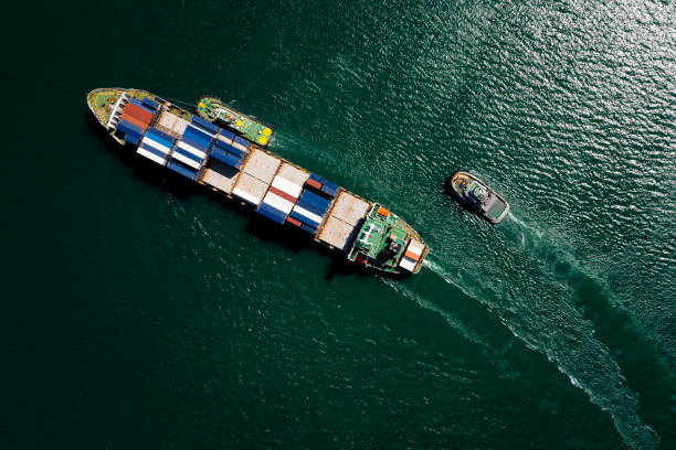 containerschiff auf dem grünen meer vollgeschwindigkeitscontainer für logistik, import export, business und industrie durch schifffahrt oder transport weltweite seefracht - tugboat stock-fotos und bilder