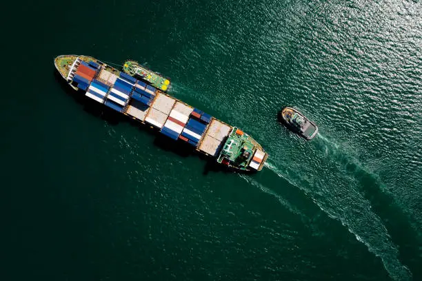 Aerial top view container ship sailing on the green sea full speed container for logistics, import export, business and Industry by shipping or transportation Worldwide ocean freight