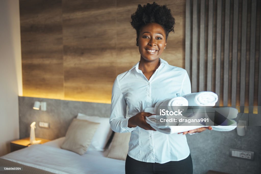 Hotel maid bringing fresh towels to the room. Hotel maid bringing fresh towels to the room. Maid clean the room and replace the bedsheets and towels. Maid with fresh towels in hotel room Hotel Stock Photo