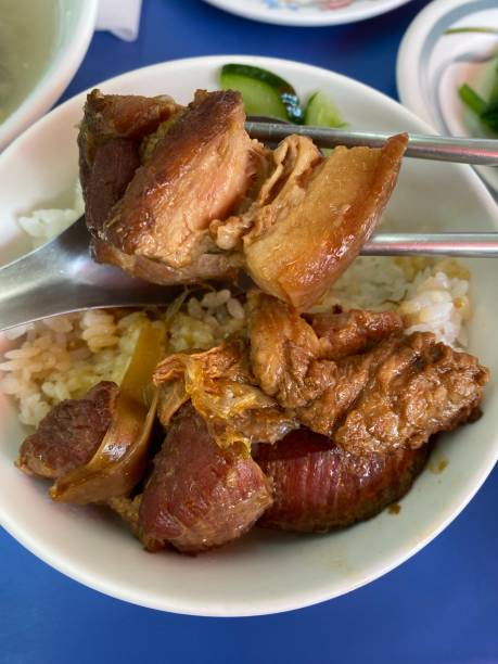A hand holding a bowl of Rice, served with smoked pork, cucumber and ginger