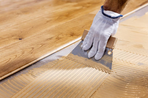 worker apply adhesive for 3 layer parquet flooring stock photo