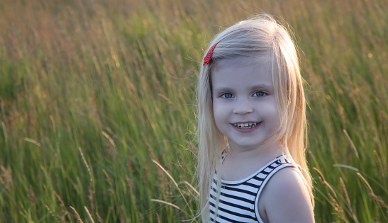 Headshot of happy toddler girl, outdoor portrait with natural light.