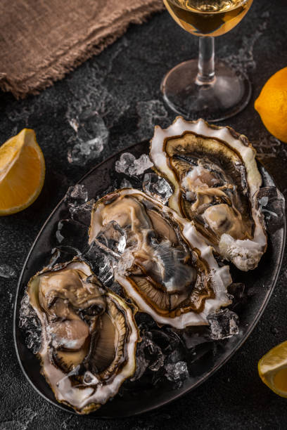 istock Fresh oysters close-up on ice served with lemon and wine. 1366065827
