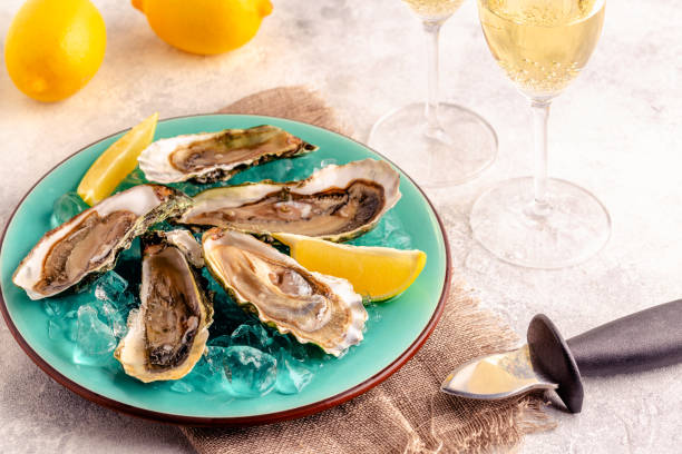 istock Opened fresh oysters on a blue plate, served with lemon and ice. 1366065980