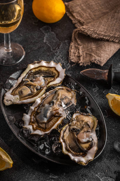 istock Fresh oysters close-up on ice served with lemon and wine. 1366066747