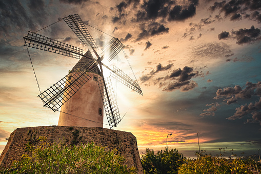 Old traditional windmill in majorca during sunset, with sunlight behind the mill, spain