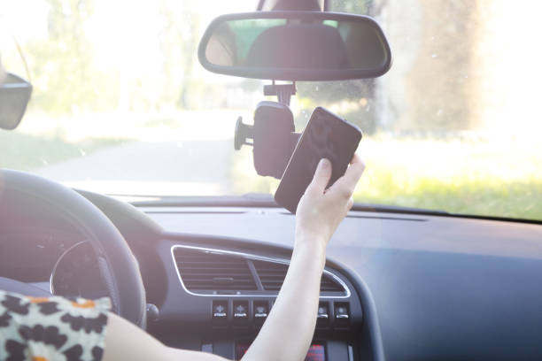 istock Woman inserting her cell phone in car phone holder 1366067198