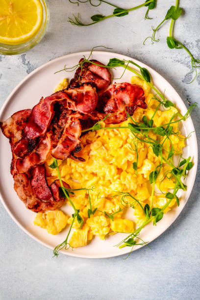 Traditional breakfast scrambled eggs with fried bacon stock photo