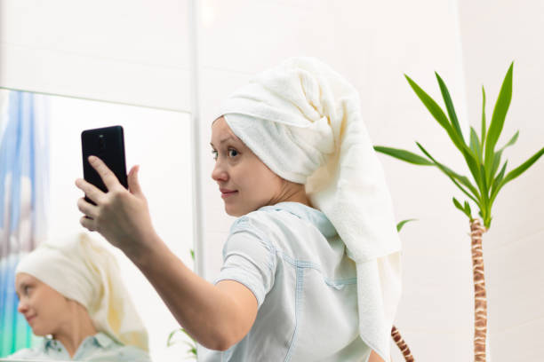 istock A young woman with a white towel on her head in a bright bathroom communicates with a smartphone with a friend in social networks. Reflection in the mirror. Selective focus 1366069361